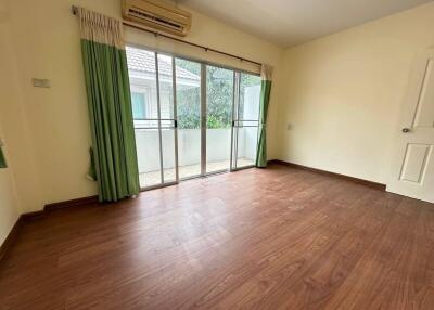 Empty bedroom with large window and wood flooring