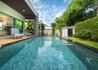 Outdoor swimming pool with adjacent seating area and lush greenery