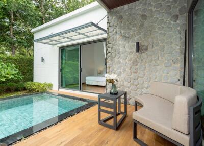 Patio with pool and seating area next to a stone wall