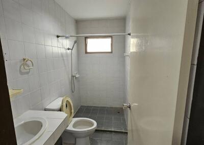 Bathroom with white tiles, toilet, sink, and shower area