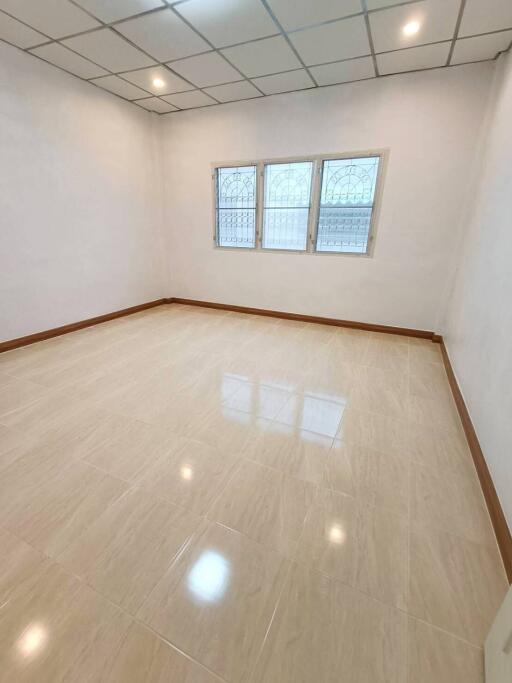 Spacious empty bedroom with tile flooring and windows