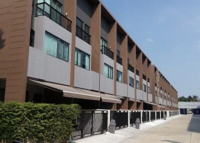 Exterior view of a multi-story residential building with multiple units and a gated entrance