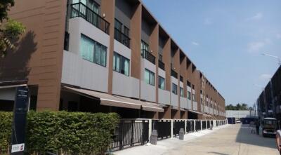 Exterior view of a multi-story residential building with multiple units and a gated entrance