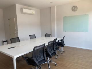 Modern meeting room with a long table, chairs, whiteboard, and air conditioning