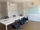 Modern meeting room with a long table, chairs, whiteboard, and air conditioning