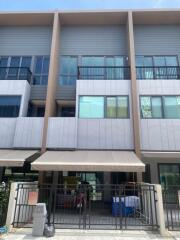 Exterior view of a multi-story residential building with balconies and gated entrance