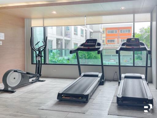 Indoor gym with exercise equipment and large windows