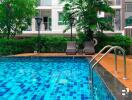 Swimming pool with lounge chairs and lush greenery