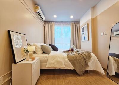 Cozy bedroom with bed, nightstand, wall art, and a large window.