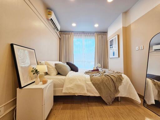 Cozy bedroom with bed, nightstand, wall art, and a large window.