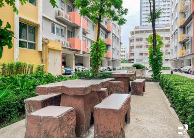 Outdoor seating area with stone tables and benches, surrounded by apartment buildings