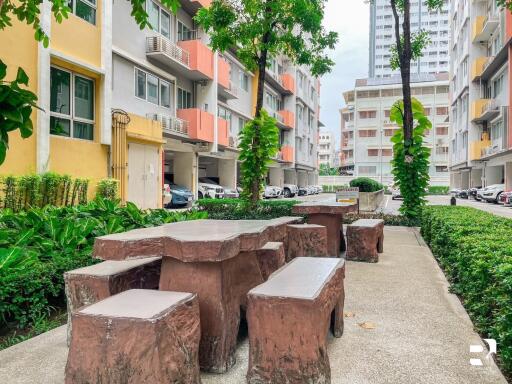 Outdoor seating area with stone tables and benches, surrounded by apartment buildings