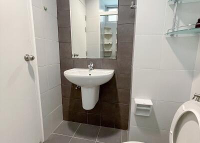 Modern bathroom with tiled walls and floor, featuring a wall-mounted sink and toilet