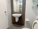 Modern bathroom with tiled walls and floor, featuring a wall-mounted sink and toilet