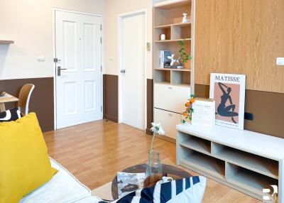 Modern living room with wooden floor, white door, shelving, and art decorations