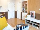 Modern living room with wooden floor, white door, shelving, and art decorations