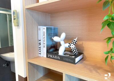 A bathroom shelf decorated with books and an artistic balloon dog sculpture