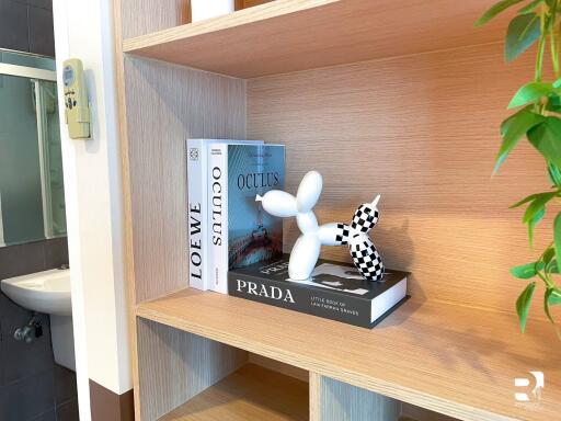 A bathroom shelf decorated with books and an artistic balloon dog sculpture