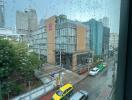 View of a rainy city street with buildings and cars from a window