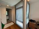 Hallway with wooden flooring, window blinds, and view into bathroom