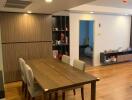 Modern dining area with wooden table and chairs, open to living space.