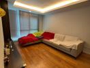 Living room with wooden floor, L-shaped couch, and large windows with blinds