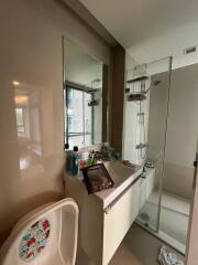 Modern bathroom with a sink, mirror, shower area, and baby chair