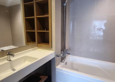 Modern bathroom with sink, mirror, bathtub, and shelving unit