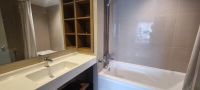 Modern bathroom with sink, mirror, bathtub, and shelving unit