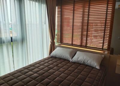 A cozy bedroom with large window and brown blinds