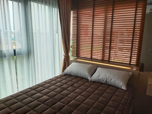 A cozy bedroom with large window and brown blinds