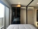 Bedroom with large window, mirrored closet, and air conditioning units