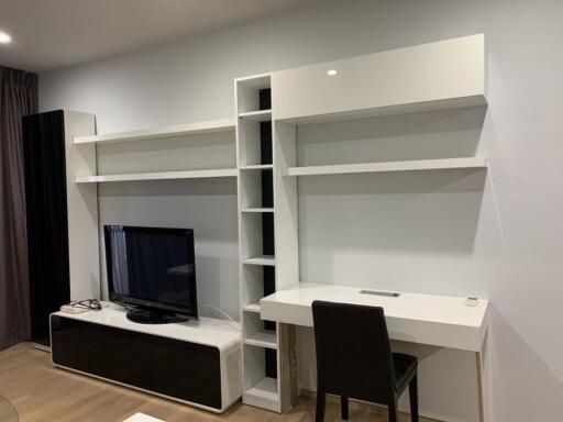 Living room with TV, shelving unit, and desk