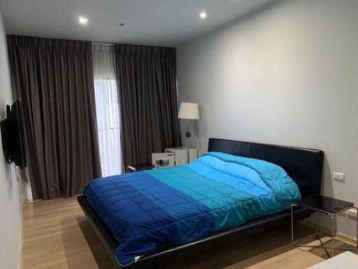 Modern bedroom with blue bedding and floor-to-ceiling curtains