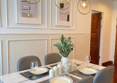 Modern dining area with table set for four, contemporary lighting, and framed artwork