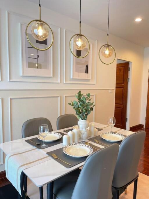 Modern dining area with table set for four, contemporary lighting, and framed artwork