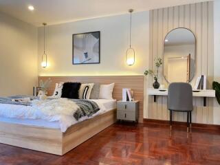 Spacious and modern bedroom with wooden floors and a cozy bed