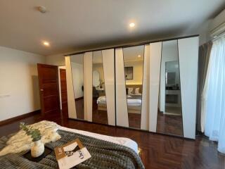 Bedroom with mirrored wardrobe and wooden flooring