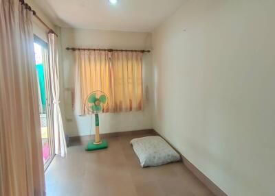 Minimalist bedroom with pillow on the floor and a standing fan, natural light coming through a window and glass door