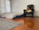 Bedroom with mattress on the floor and a black chair