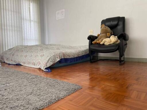 Bedroom with mattress on the floor and a black chair