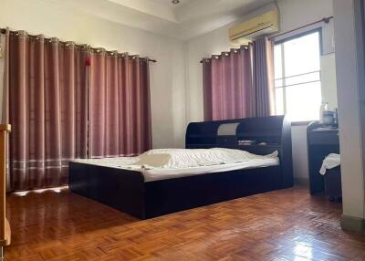 Spacious bedroom with a large bed, wooden flooring, and ample natural light