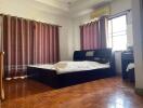 Spacious bedroom with a large bed, wooden flooring, and ample natural light