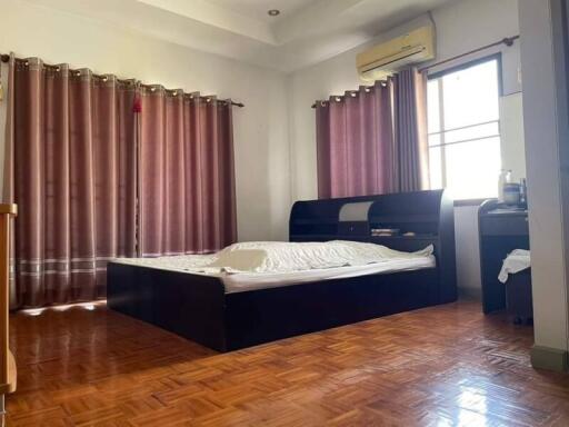 Spacious bedroom with a large bed, wooden flooring, and ample natural light