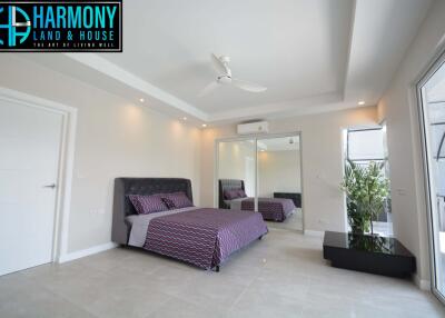 Modern bedroom with bed, mirrored wardrobe, and ceiling fan