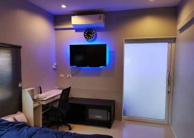 Modern bedroom with work area and wall-mounted TV