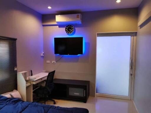 Modern bedroom with work area and wall-mounted TV