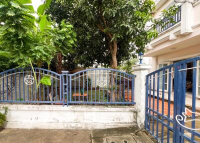 Image of a house exterior with a blue gate and garden