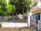 Image of a house exterior with a blue gate and garden