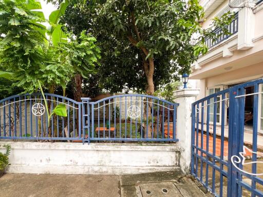 Image of a house exterior with a blue gate and garden